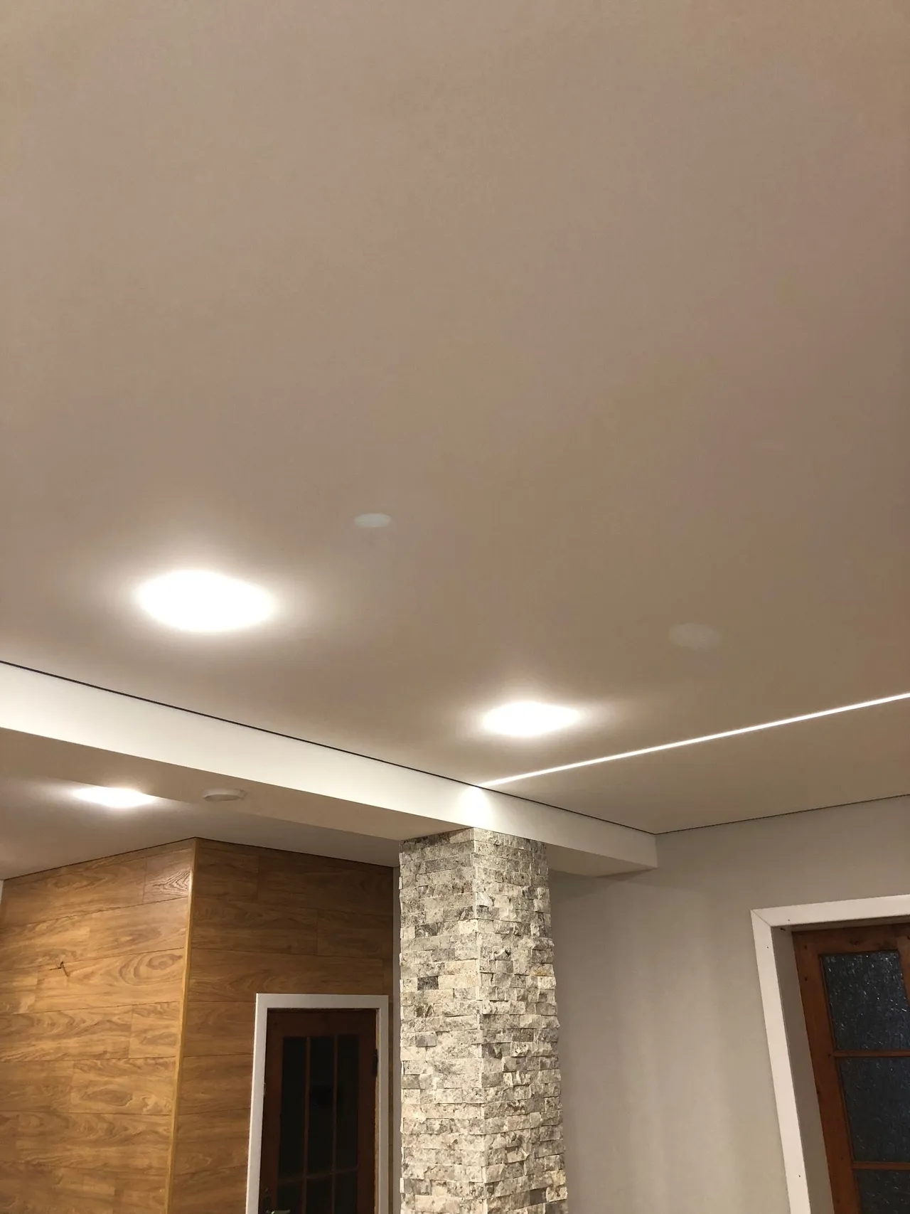 Linii de lumină și spoturi cu halogen pe un tavan alb mat